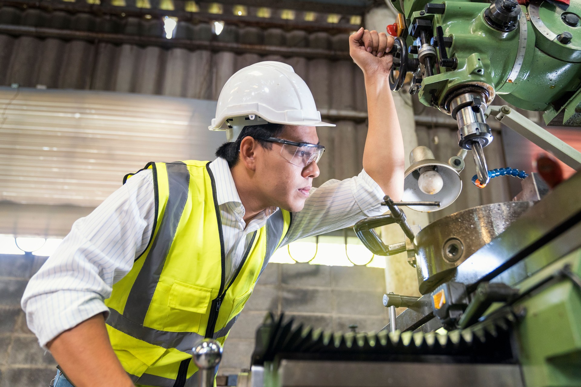 Asian Mechanical Engineer checking equipment in factory. factory workers using machine equipment in workshop. Asian mechanical engineer operating industrial lathe machine.